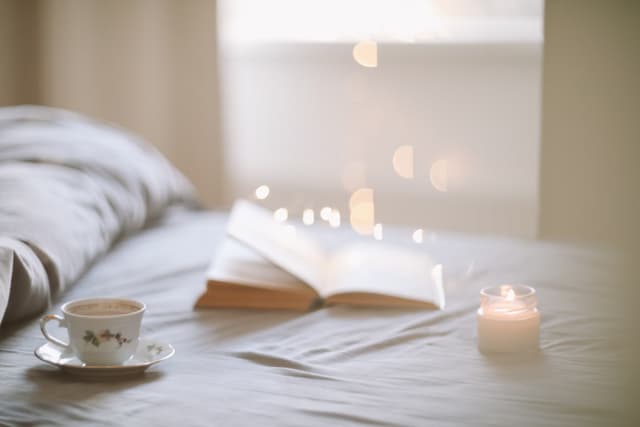 Cozy bedroomw ith book, candle and cup of tea